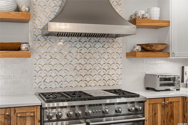 kitchen with wall chimney range hood, stainless steel stove, and tasteful backsplash