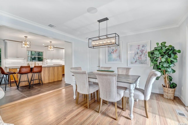 dining space featuring crown molding and light hardwood / wood-style flooring