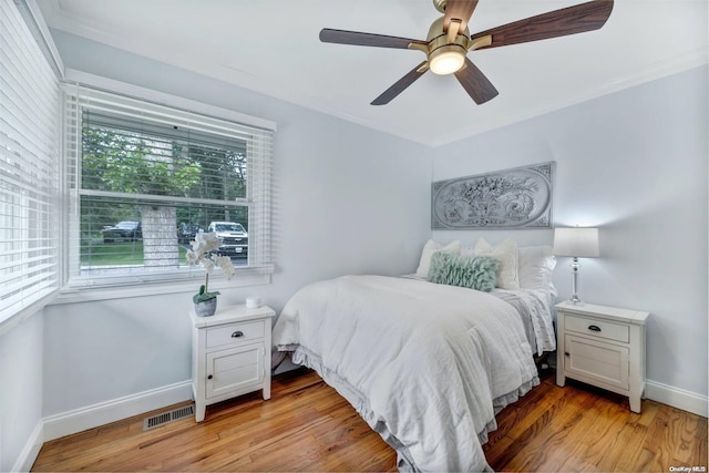 bedroom with ceiling fan, crown molding, and light hardwood / wood-style floors