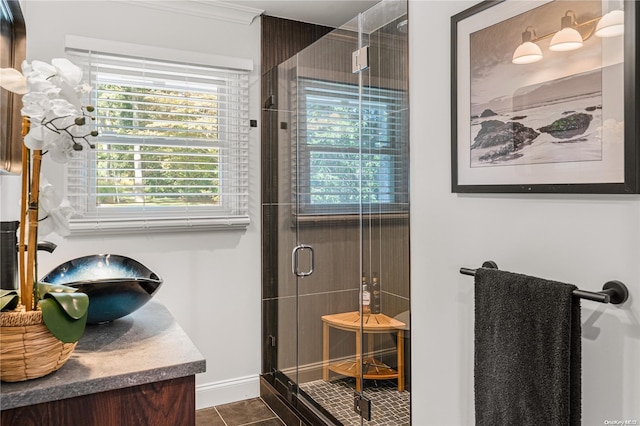 bathroom with tile patterned floors, a shower with door, vanity, and ornamental molding