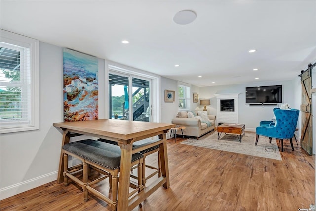 dining area with a barn door and light hardwood / wood-style floors