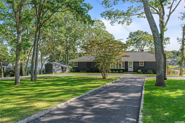 ranch-style house featuring a front lawn and an outdoor structure