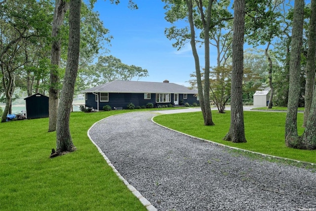 view of front facade featuring a storage shed and a front lawn