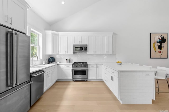 21 Montauk Hwy Unit 5, Westhampton, NY 11977 - kitchen featuring stainless steel appliances, a sink, a peninsula, backsplash, and high vaulted ceiling