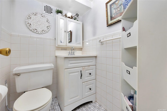 bathroom with tile patterned flooring, vanity, tile walls, and toilet