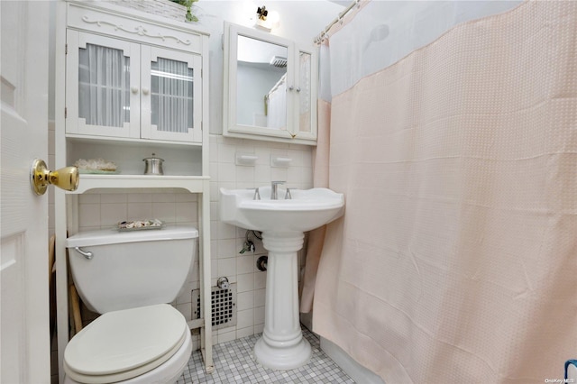 bathroom featuring toilet, tile patterned floors, and tile walls