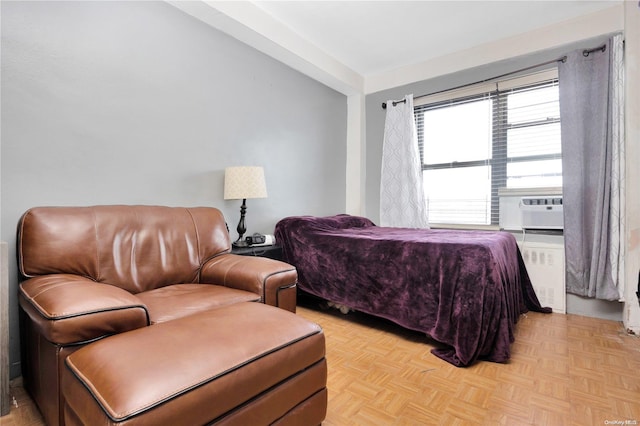 bedroom with cooling unit, radiator, and light parquet floors