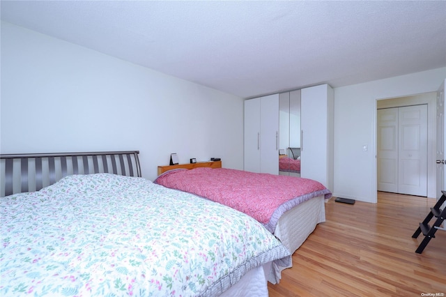 bedroom with light hardwood / wood-style floors, a textured ceiling, and a closet