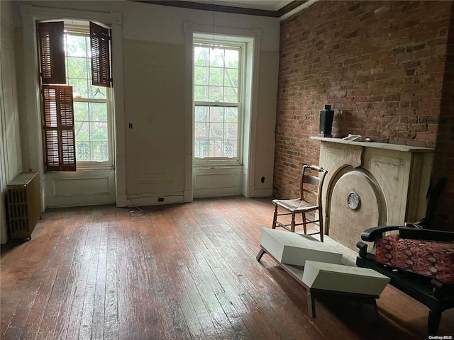 living room with light hardwood / wood-style floors, plenty of natural light, ornamental molding, and brick wall