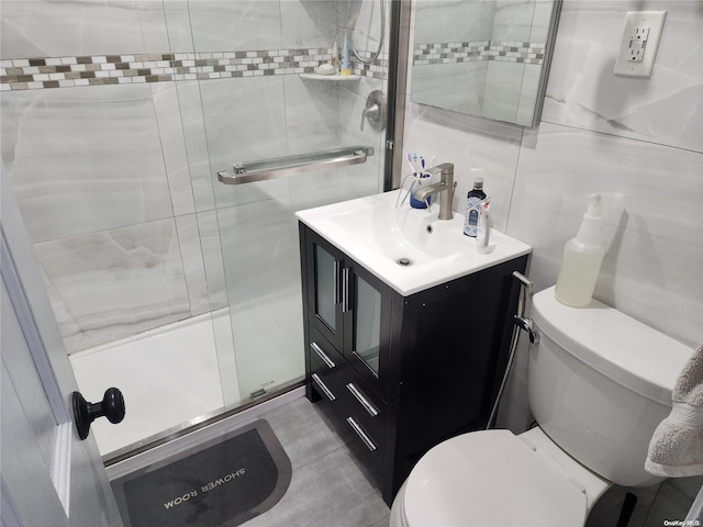 bathroom with tile walls, vanity, an enclosed shower, and toilet