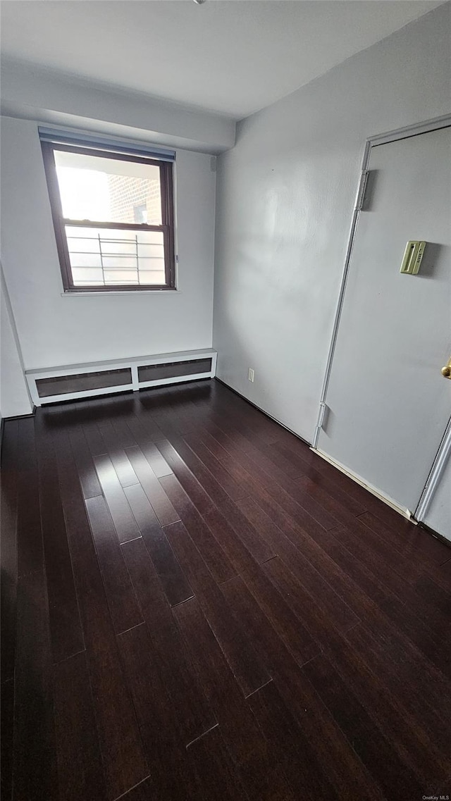 spare room with a baseboard heating unit and wood finished floors