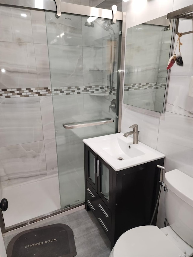 bathroom with toilet, a stall shower, tile walls, and vanity