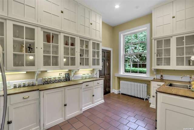 kitchen featuring white cabinets, radiator, and sink