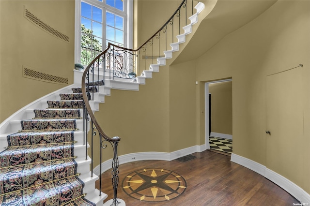 stairs featuring wood-type flooring and a high ceiling