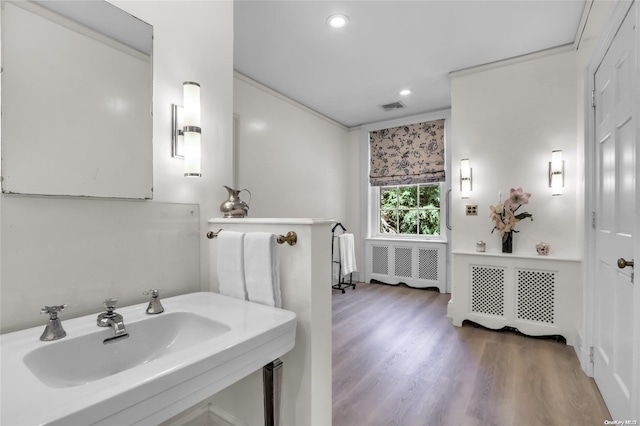 bathroom with hardwood / wood-style floors, crown molding, sink, and radiator