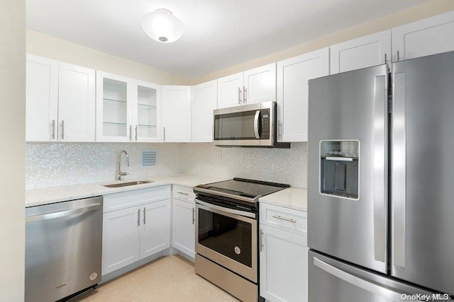 kitchen featuring decorative backsplash, light stone countertops, stainless steel appliances, sink, and white cabinets