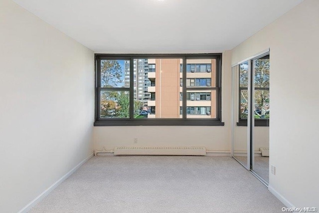 carpeted empty room featuring baseboard heating