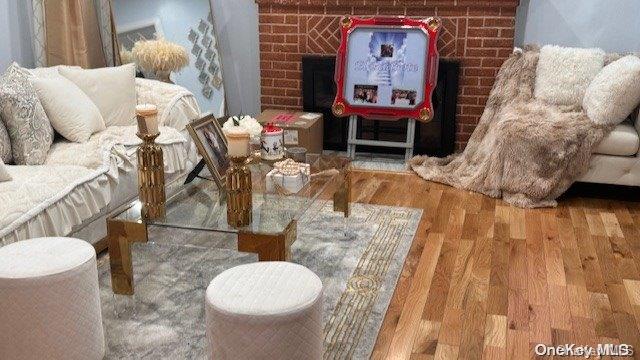 living area with a fireplace, wood-type flooring, and brick wall