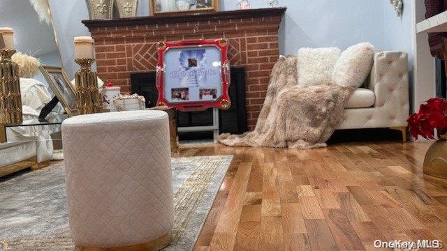 sitting room with hardwood / wood-style flooring and a brick fireplace