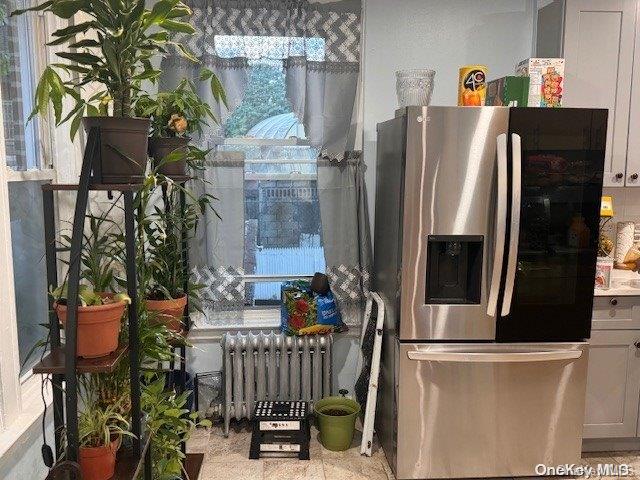 kitchen with white cabinets, stainless steel refrigerator with ice dispenser, and radiator