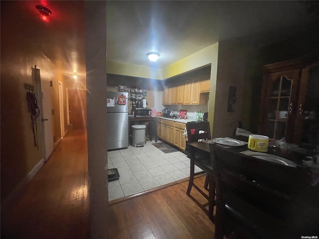 kitchen with appliances with stainless steel finishes, light hardwood / wood-style flooring, and light brown cabinetry