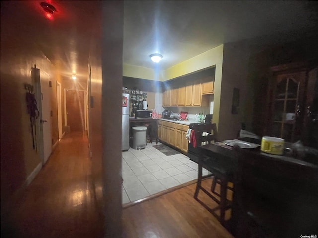 kitchen featuring black electric range, light brown cabinetry, light hardwood / wood-style floors, and fridge