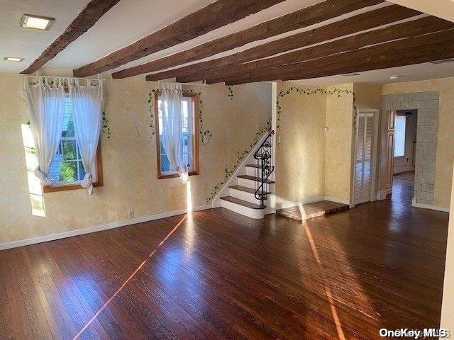 unfurnished room featuring beamed ceiling and dark wood-type flooring