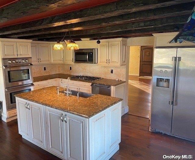 kitchen with white cabinets, stainless steel appliances, a kitchen island with sink, and sink