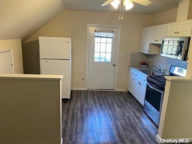 kitchen featuring sink, vaulted ceiling, dark hardwood / wood-style floors, white cabinetry, and stainless steel appliances