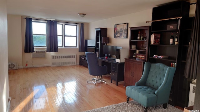 office space with light wood-type flooring, radiator, and cooling unit