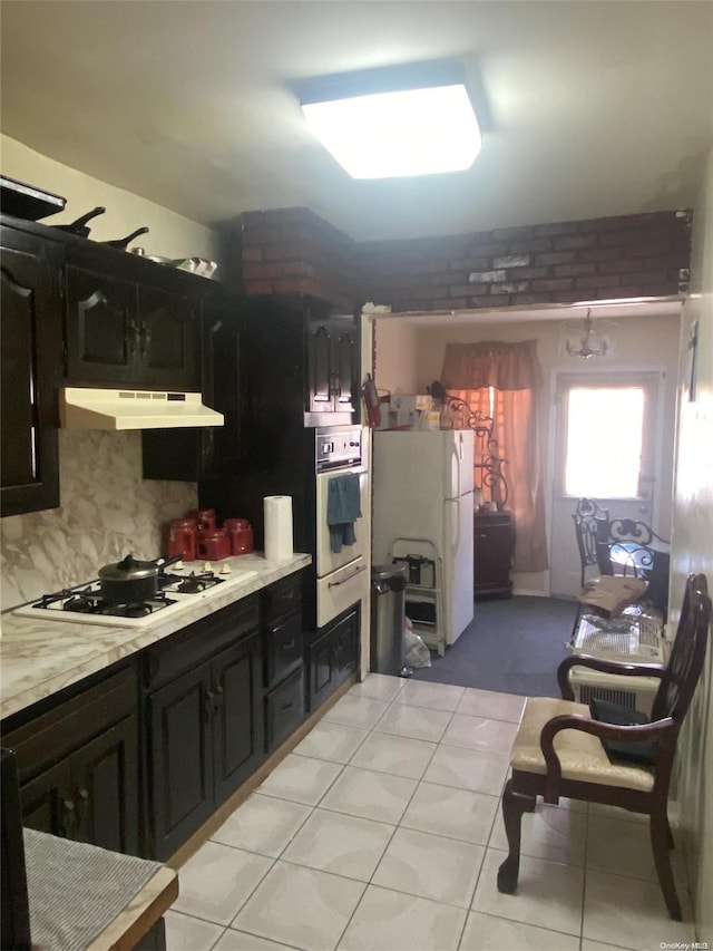 kitchen featuring decorative backsplash, light tile patterned flooring, white appliances, and range hood