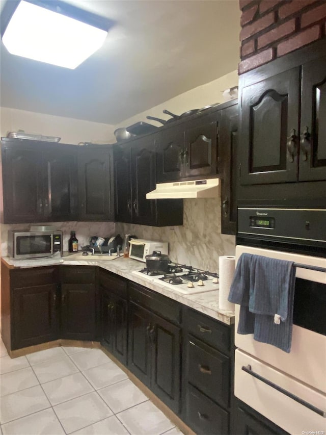 kitchen featuring white appliances, backsplash, and light tile patterned floors