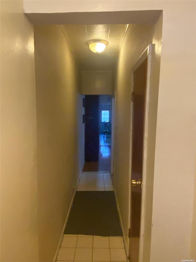 hallway featuring light tile patterned floors and crown molding