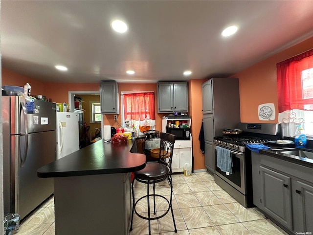 kitchen with a breakfast bar, gray cabinets, stainless steel appliances, and a wealth of natural light