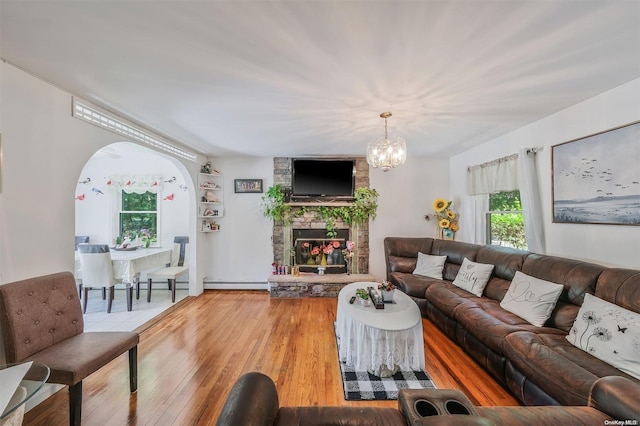 living room featuring hardwood / wood-style floors, a fireplace, a wealth of natural light, and an inviting chandelier