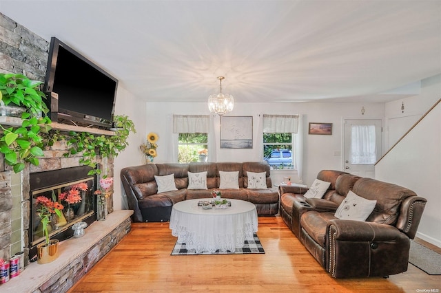 living room featuring a fireplace, an inviting chandelier, and light hardwood / wood-style flooring