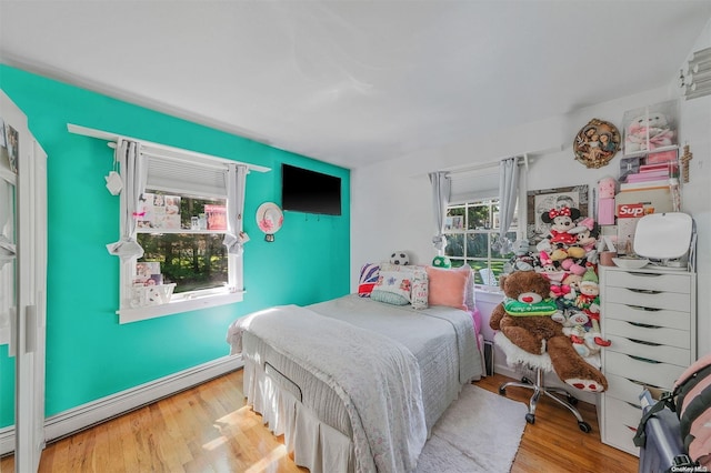 bedroom with light hardwood / wood-style flooring and baseboard heating