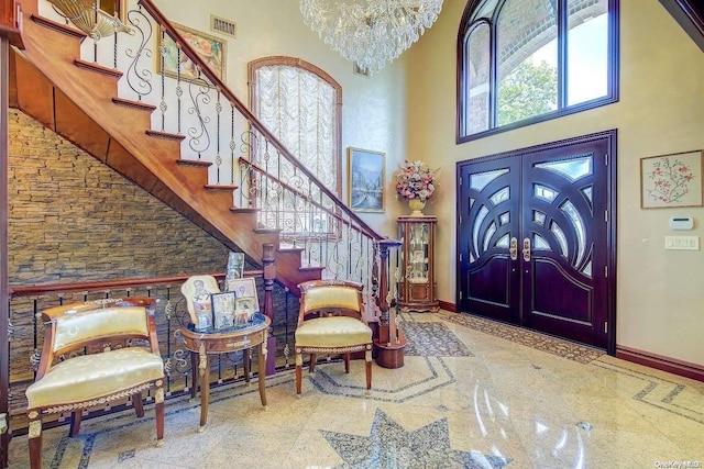 entrance foyer featuring an inviting chandelier, a towering ceiling, and french doors