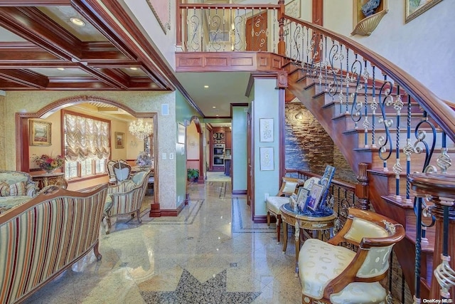 foyer entrance featuring a towering ceiling, beamed ceiling, coffered ceiling, and ornamental molding