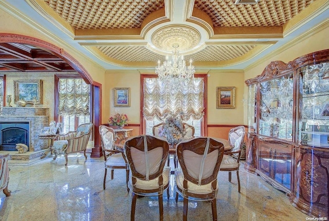 dining room featuring a fireplace, a chandelier, coffered ceiling, and ornamental molding