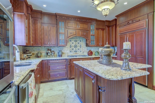 kitchen with a center island, tasteful backsplash, light stone counters, and sink