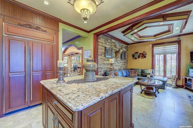 kitchen with light stone countertops, a center island, and ornamental molding