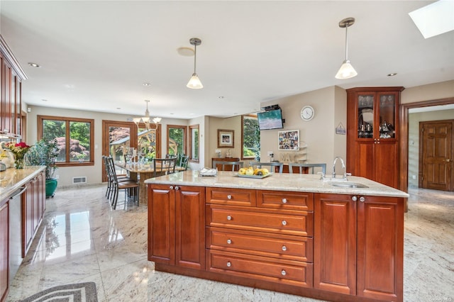 kitchen featuring decorative light fixtures, light stone counters, and sink