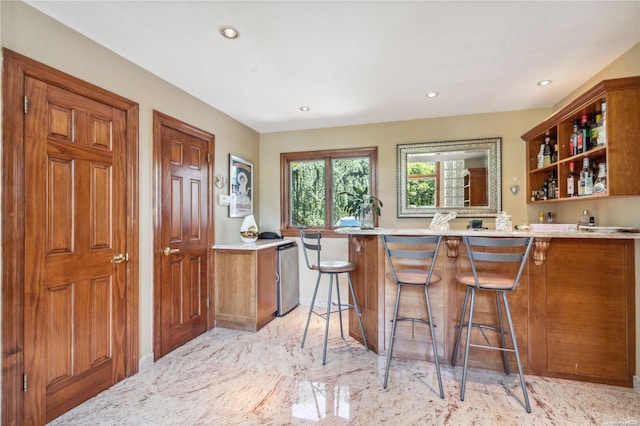 kitchen with stainless steel dishwasher, a kitchen bar, and kitchen peninsula