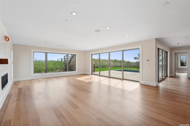451 Dune Rd, Westhampton Beach, NY 11978 - unfurnished living room with healthy amount of natural light, baseboards, light wood-style floors, a large fireplace, and recessed lighting