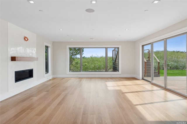 451 Dune Rd, Westhampton Beach, NY 11978 - unfurnished living room with healthy amount of natural light, light wood-style flooring, baseboards, a glass covered fireplace, and recessed lighting