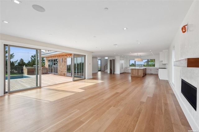 451 Dune Rd, Westhampton Beach, NY 11978 - unfurnished living room with a fireplace, light wood-style flooring, plenty of natural light, recessed lighting, and baseboards