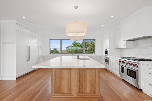 451 Dune Rd, Westhampton Beach, NY 11978 - kitchen featuring appliances with stainless steel finishes, a sink, decorative backsplash, light wood finished floors, and white cabinets