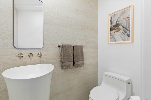 bathroom featuring toilet and tile walls