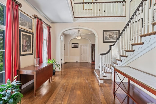 foyer with plenty of natural light, dark hardwood / wood-style flooring, ornamental molding, and a high ceiling